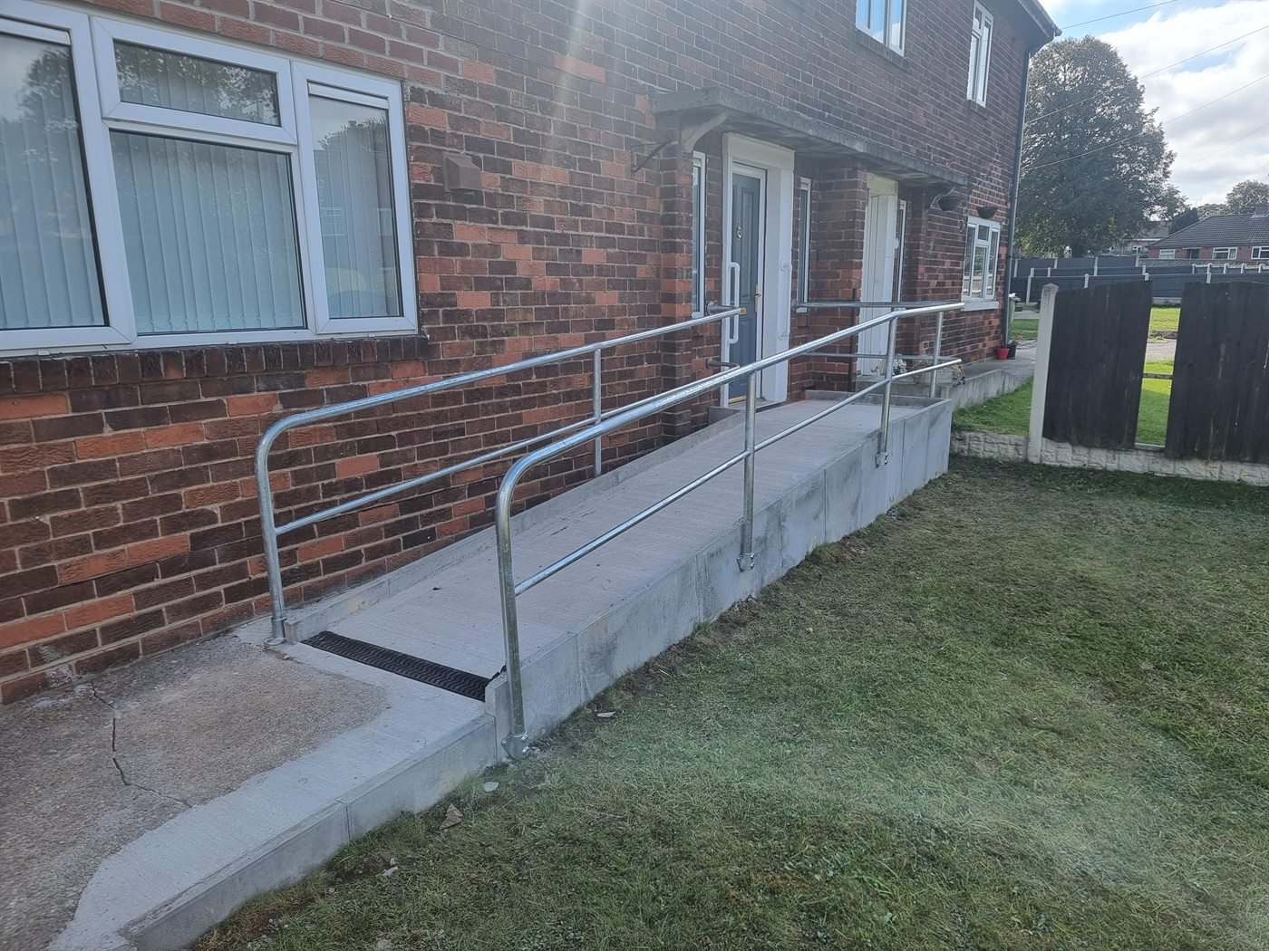 Long galvanised metal handrail fitted along an access ramp